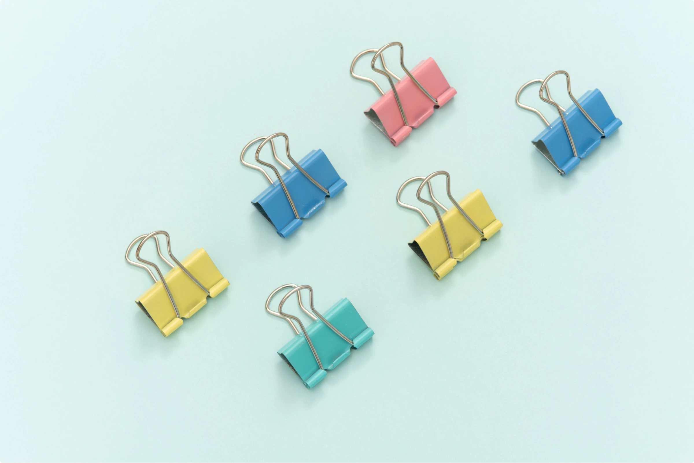 A pattern of colorful paper clips on a blue background for back to school projects