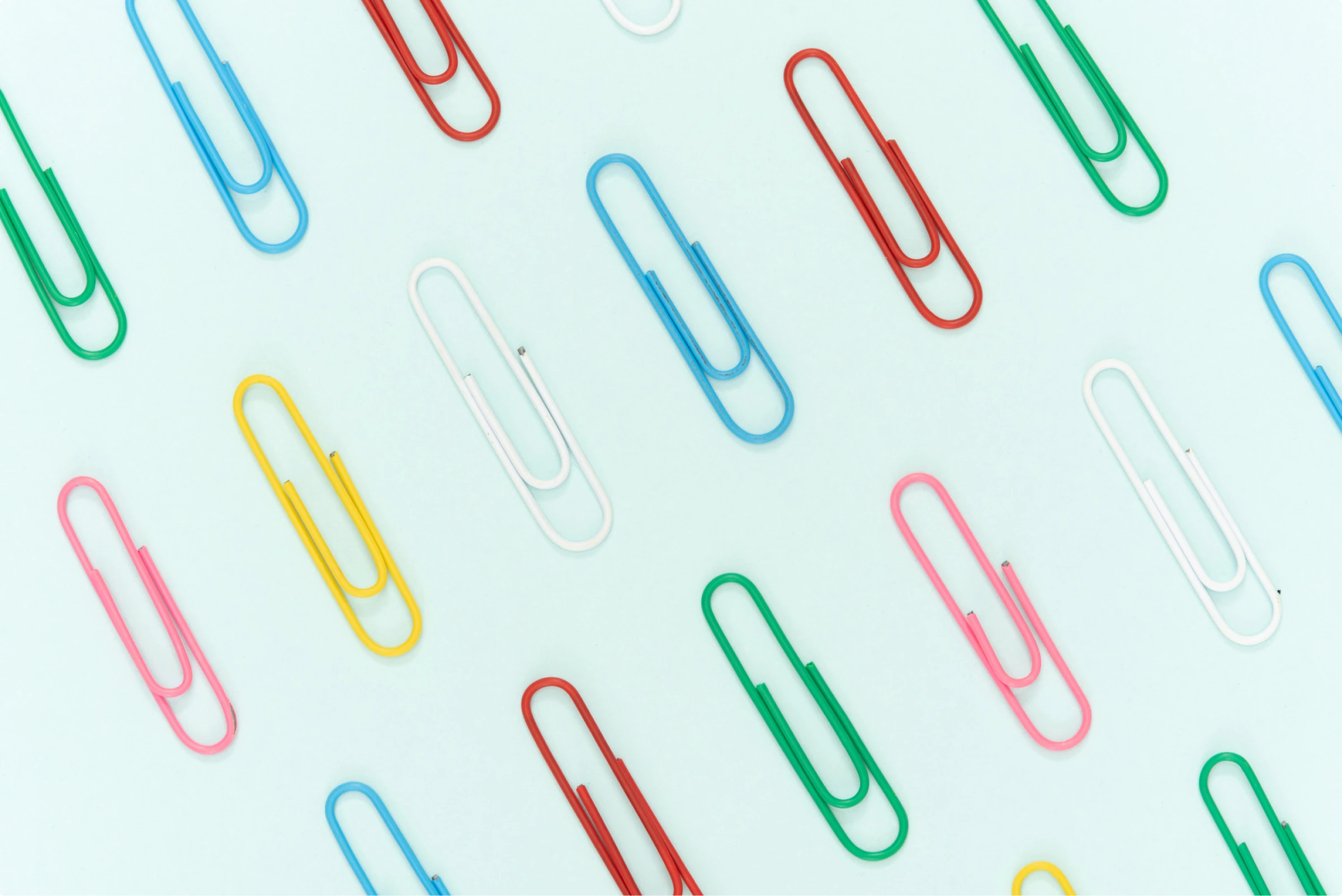 A pattern of colorful paper clips on a blue background for back to school projects